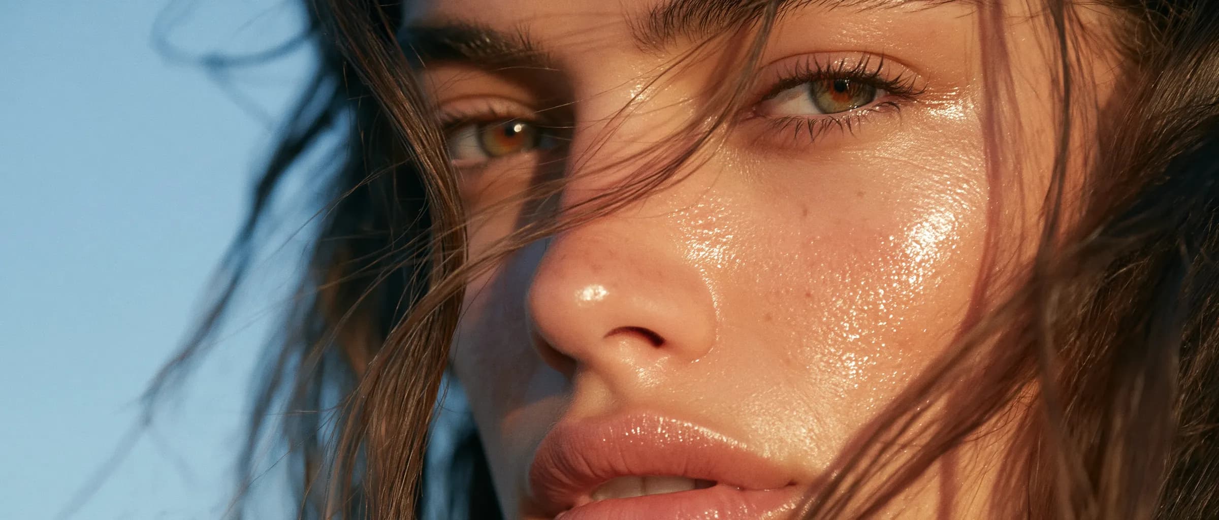 A woman outdoors against open sky, skin luminous in clear daylight